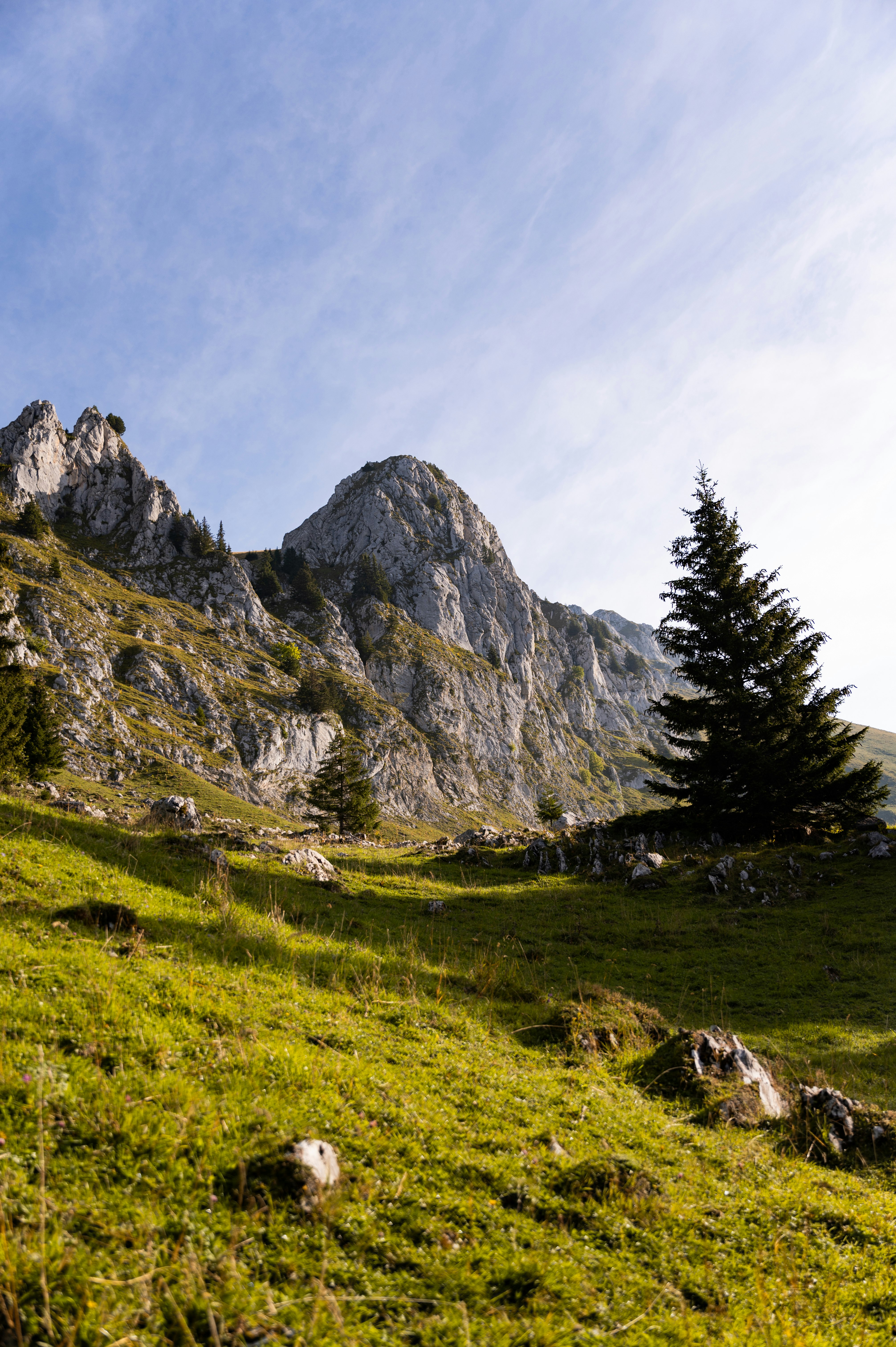 green grass field near mountain under white clouds during daytime